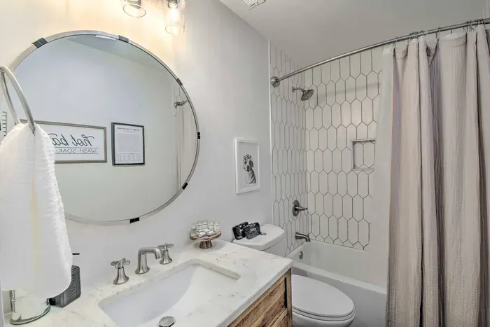 Experience a touch of luxury in your well-appointed bathroom, complete with a round mirror, fresh towels, a refreshing shower, and all the essential amenities. 
