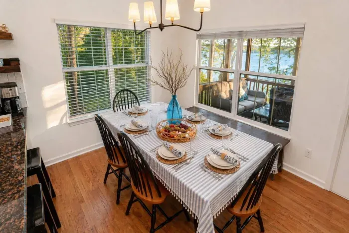 The indoor dining table fits everyone — lake light through the windows, no one squeezed into a corner. Seating for 8 & kitchen bar seating for 3.