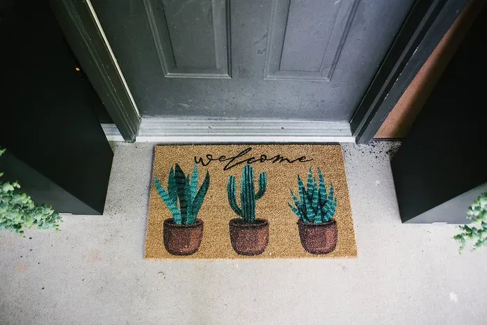 A charming door mat featuring three potted plants, welcoming you to a refreshing and nature-inspired abode