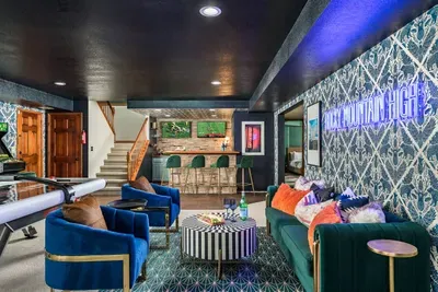 Downstairs game room and lounge with air hockey, arcade pool, and two TVs mounted behind a bar for easy sports watching.