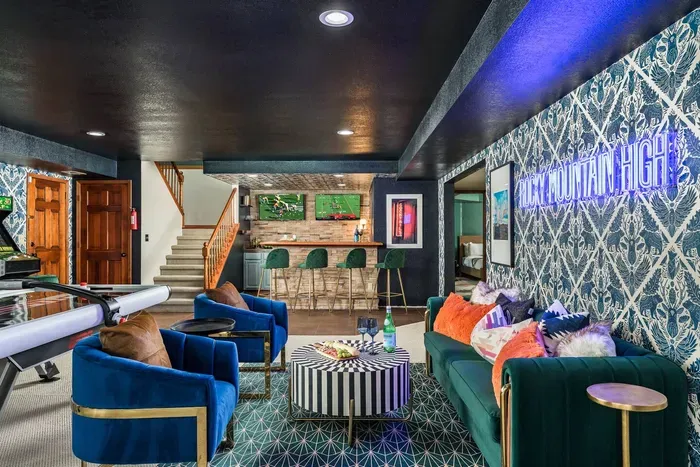Downstairs game room and lounge with air hockey, arcade pool, and two TVs mounted behind a bar for easy sports watching.