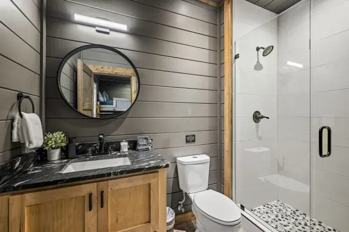 Modern bathroom with shower, black marble vanity, and rustic wood finishes.
