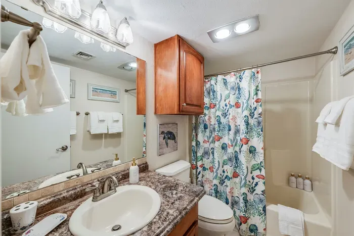 Inviting bathroom with granite vanity, shower, and colorful sea décor