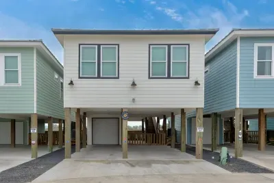 Front view of a raised coastal home featuring a ground-level garage.