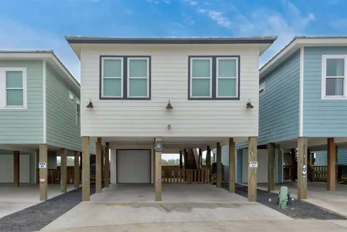 Front view of a raised coastal home featuring a ground-level garage.
