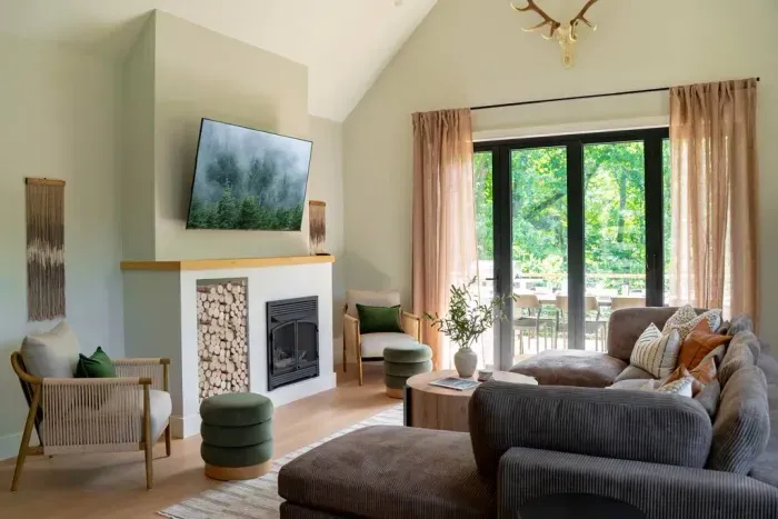Scandinavian-inspired living room with vaulted ceilings, bright and airy, plus a 65" smart tv. The indoor fireplace is decorative only and does not ignite, per insurance and safety regulations.
