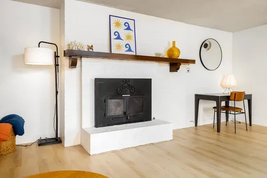 Stylish and cozy living room featuring unique Southwestern artwork, a beautifully designed wood-burning fireplace, and warm wood accents that create a charming, homey vibe.
