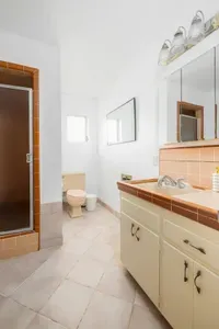 Bright and spacious full bathroom featuring a walk-in shower, vintage tile accents, and plenty of counter space. Equipped with all the essentials for a comfortable and convenient stay.