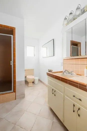 Bright and spacious full bathroom featuring a walk-in shower, vintage tile accents, and plenty of counter space. Equipped with all the essentials for a comfortable and convenient stay.