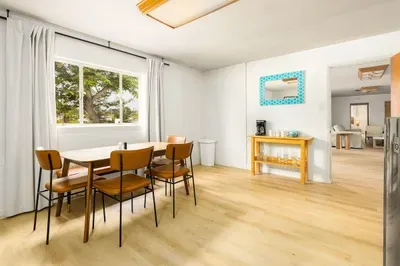 Bright and airy dining space with mid-century modern furnishings, a large picture window with lush views, and playful accent décor that adds charm and character to every meal!