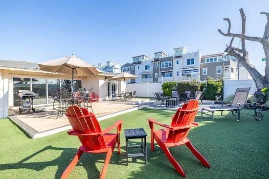 Soak up the sun on the spacious wooden deck. The vibrant red Adirondack chairs and modern grey seating offer plenty of spots to unwind. From morning coffee to sunset drinks, this outdoor area is your private sanctuary.