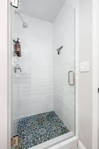 Invigorating walk-in shower with a unique pebble floor and modern fixtures—designed for total relaxation.