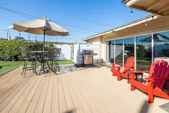 A vibrant backyard retreat with endless seating, a BBQ grill, and plenty of space to relax under the sun or shade.