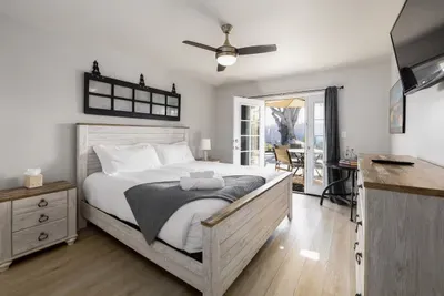 Drift off to sleep in this bright and airy bedroom, designed with a charming coastal farmhouse aesthetic. Enjoy high-quality linens, a cooling ceiling fan, and the convenience of direct access to the outdoor living space.