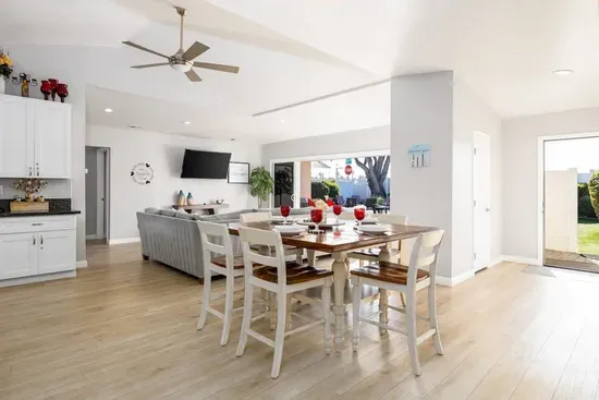 This stylish dining nook comfortably seats four guests with its modern high chairs and warm wooden table. The bright, airy atmosphere enhanced by views of the outdoors and easy access to both the kitchen and living room makes every meal special.