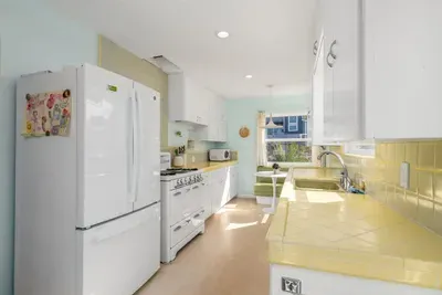Enjoy your meals at the charming built-in dinette with a sage green banquette, perfectly positioned by the window.