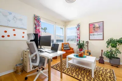 Large windows flood the room with natural light and offer a peaceful outlook, complemented by vibrant, floral-print curtains.