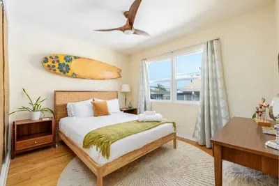 Sink into high-quality linens and a plush queen-sized mattress, complete with a cozy mustard-yellow throw and decorative pillows.