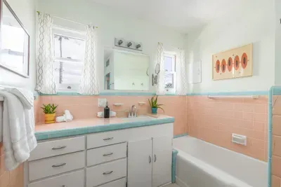 Features stunning pink and turquoise tiling throughout, including a coordinated tiled countertop and a built-in bathtub surround.