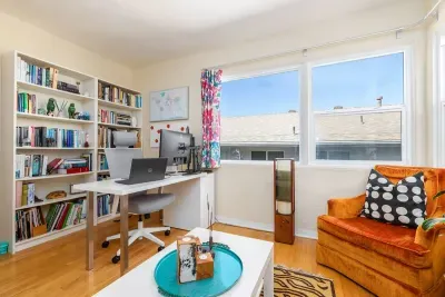 Features a spacious white workstation with an ergonomic office chair, a high-definition external monitor, and a laptop setup for seamless productivity.