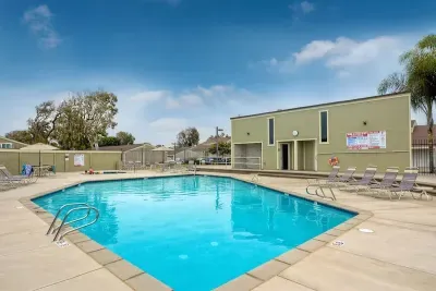 This is the spacious outdoor swimming pool. It is surrounded by a concrete deck with several lounge chairs, offering a relaxing space for guests.