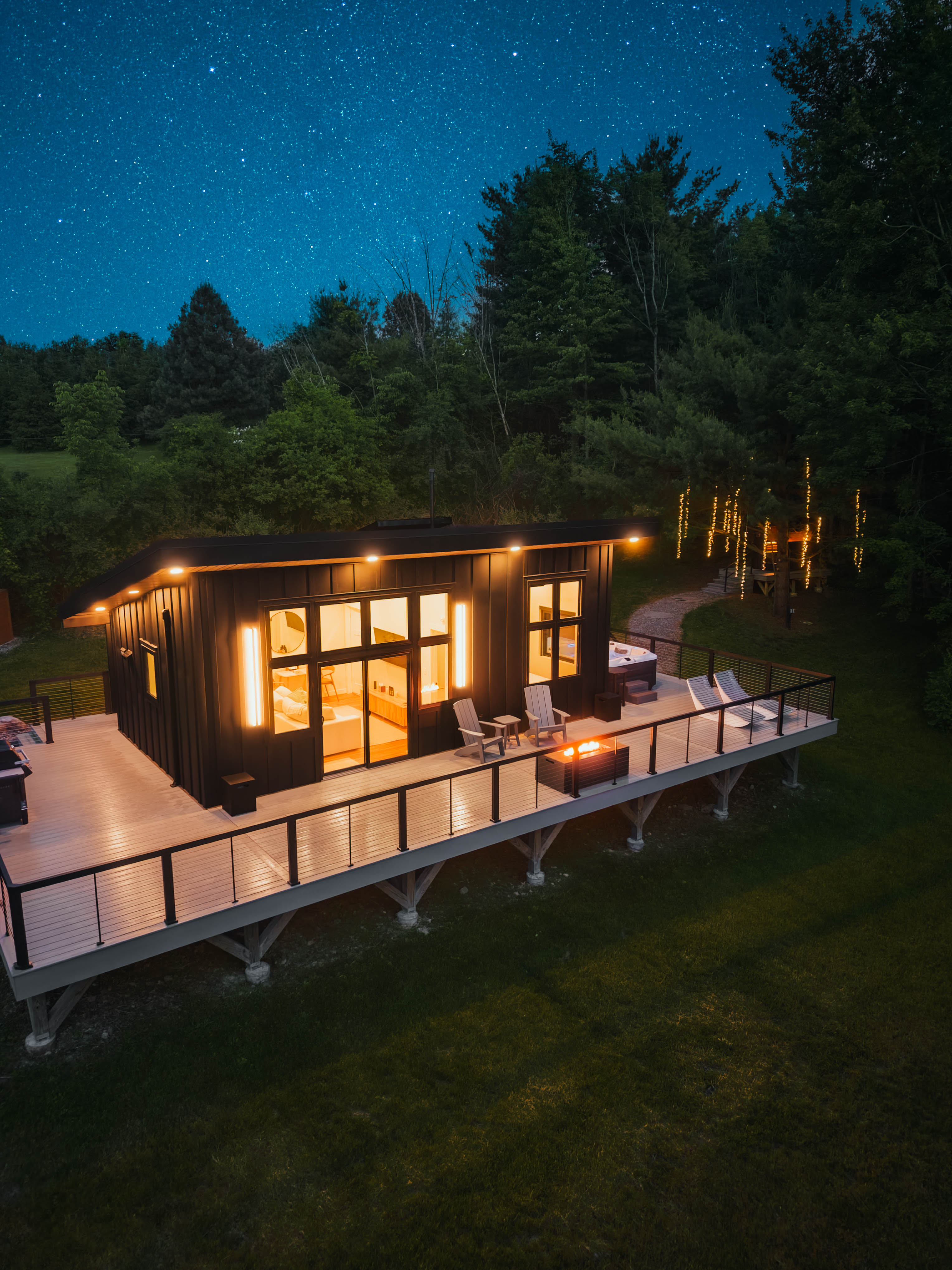 Tucked away on 24 acres of private woods, The Kimberly offers the perfect mix of modern design and peaceful seclusion. 1,000 sq ft. wrap around deck including hot tub, cold plunge, fire pit, grill and loungers. A stone path leads to the Kuro sauna.
