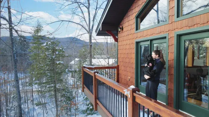 Woman holding her dog on the patio of New Hampshire winter rental