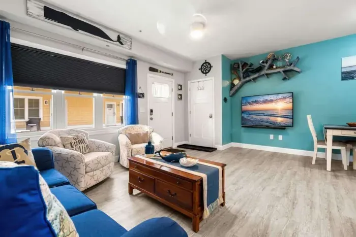 Open living room & kitchen, with mounted smart TV, Dining table, strong WiFi, sleeper sofa and fully-equipped kitchen