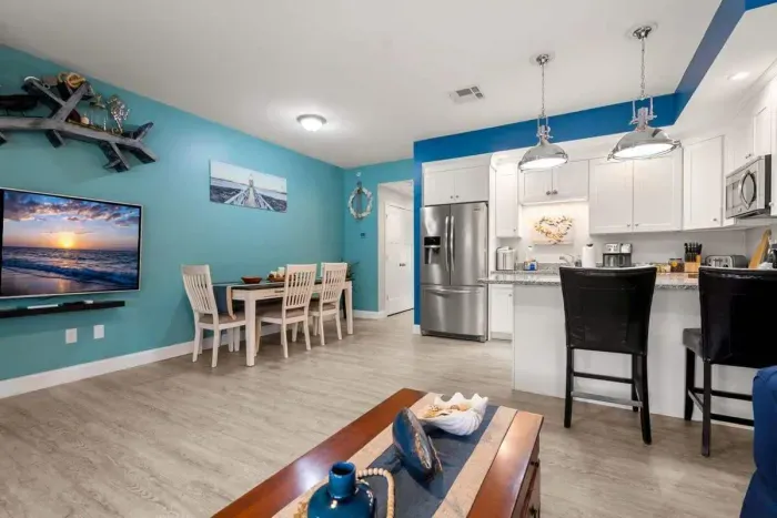 Open living room & kitchen, with mounted smart TV, Dining table, strong WiFi, sleeper sofa and fully-equipped kitchen