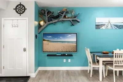 Open living room & kitchen, with mounted smart TV, Dining table, strong WiFi, sleeper sofa and fully-equipped kitchen