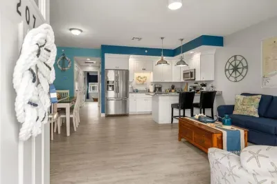 Open living room & kitchen, with mounted smart TV, Dining table, strong WiFi, sleeper sofa and fully-equipped kitchen