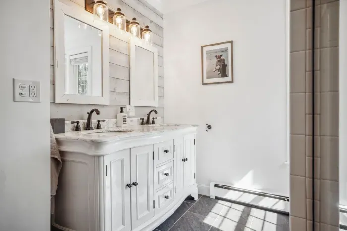 The primary bedroom ensuite with tiled shower, double vanity, and provided clean towels