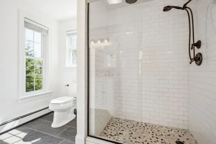 The primary bedroom ensuite with tiled shower, double vanity, and provided clean towels