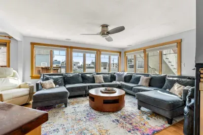 The family room with a comfy and large sectional couch, Sonos sound system, smart TV, and a gas fireplace