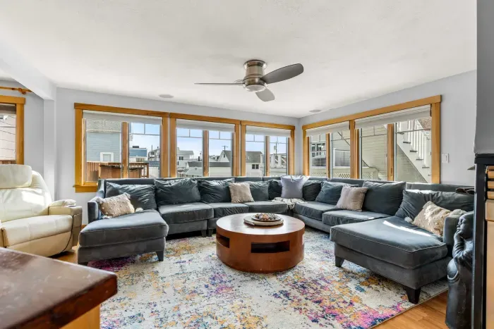 The family room with a comfy and large sectional couch, Sonos sound system, smart TV, and a gas fireplace
