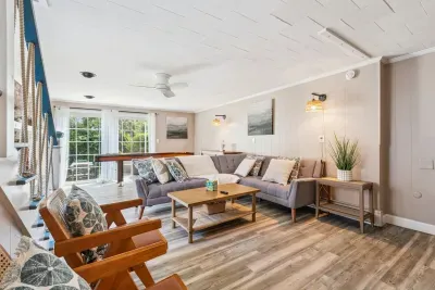 Back unit living room featuring a large sectional couch and smart TV with the ability to log into personal streaming platforms. Note: Fireplace is inoperable. There is a shuffleboard table here too!