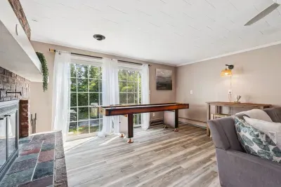 Back unit living room featuring a large sectional couch, smart TV with the ability to log into personal streaming platforms, and shuffle board!