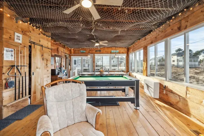 The closed in porch - this area is heated and cooled with it's own mini-split system. There is a pool/air hockey table, seating for 10 at the table, and another seating area with a sectional and chairs