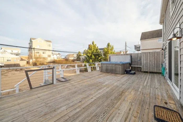 The deck! Featuring a gas grill, and hot tub. Access to the house is via a flight of stairs leading up to the deck, pictured on the left. There is furniture out here in the summer months. It is stored away in the off-season months