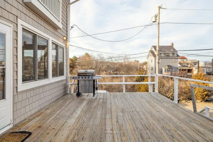 The deck! Featuring a gas grill, and hot tub. Access to the house is via a flight of stairs leading up to the deck, pictured on the right. There is furniture out here in the summer months. It is stored away in the off-season months