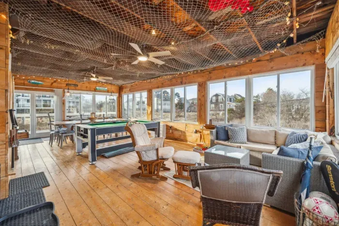 The closed in porch - this area is heated and cooled with it's own mini-split system. There is a pool/air hockey table, seating for 10 at the table, and another seating area with a sectional and chairs