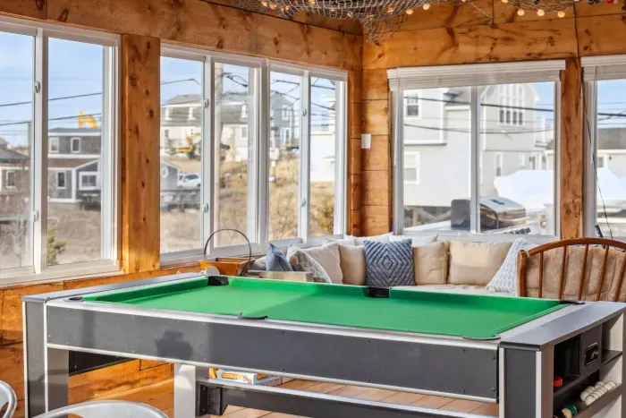 The closed in porch - this area is heated and cooled with it's own mini-split system. There is a pool/air hockey table, seating for 10 at the table, and another seating area with a sectional and chairs