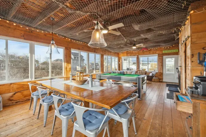 The closed in porch - this area is heated and cooled with it's own mini-split system. There is a pool/air hockey table, seating for 10 at the table, and another seating area with a sectional and chairs