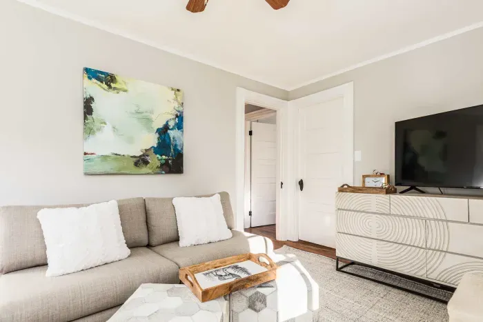 Cozy living room with comfy couch and chairs, and a smart TV. Access to the front balcony is from this room.