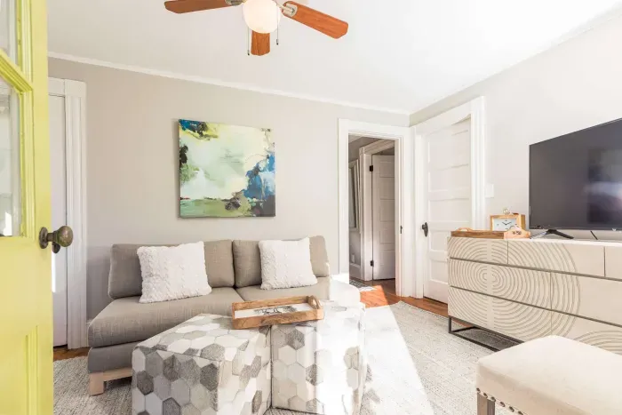 Cozy living room with comfy couch and chairs, and a smart TV. Access to the front balcony is from this room.
