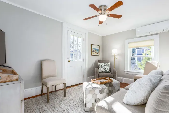 Cozy living room with comfy couch and chairs, and a smart TV. Access to the front balcony is from this room.