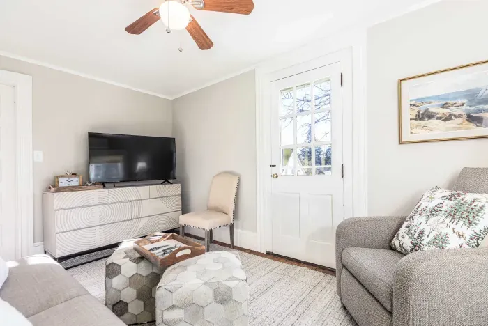 Cozy living room with comfy couch and chairs, and a smart TV. Access to the front balcony is from this room.