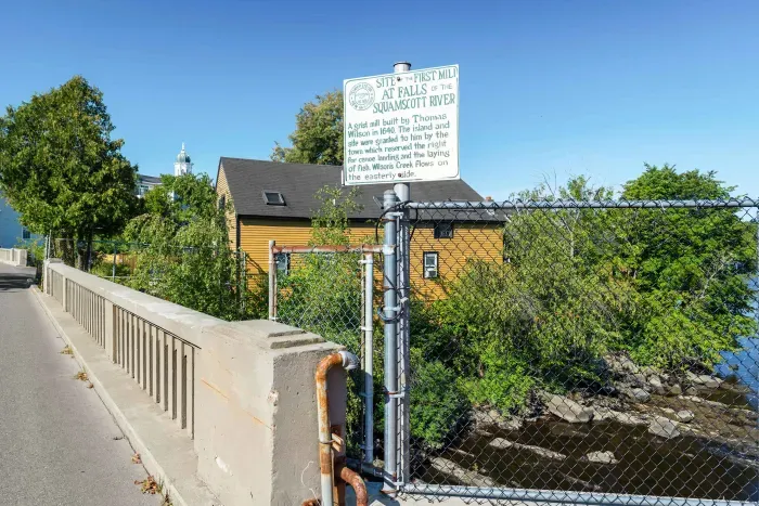 Scenic view of the historic mill area along the Squamscott River, highlighting the property’s waterfront surroundings. This sign highlights a portion of the property's history.