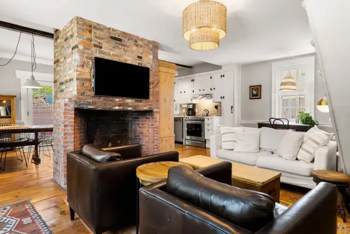 Living room with smart TV, couch, accent chairs and dedicated "work-from-home" desk. The fireplace is inoperable.