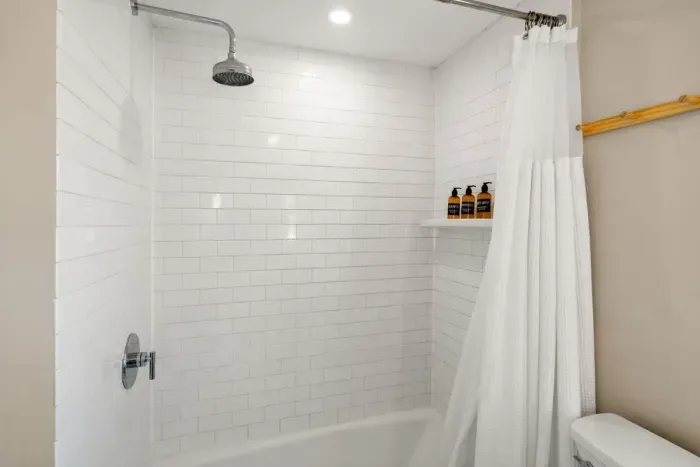 full bathroom with tiled shower tub, and stackable washer/dryer, located on the second level.